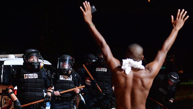 A protester raises his arms in front of officers in Charlotte, N.C., Tuesday, Sept. 20, 2016. Authorities used tear gas to disperse protesters in an overnight demonstration that broke out Tuesday after Keith Lamont Scott was fatally shot by an officer at an apartment complex.