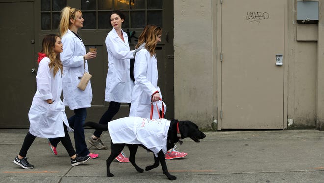 People head to a rally including a "lab in a lab coat" named Rodger and his owner Cate Tambeaux, holding the leash, at the March for Science at Cal Anderson Park in Seattle, Washington.