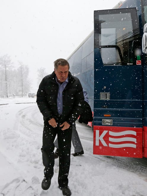 Kasich zips up his jacket as he steps off his campaign bus in Atkinson, N.H., on Feb. 5, 2016.
