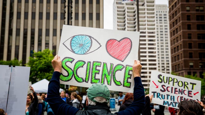 People hold signs during the March for Science in downtown Cincinnati.
