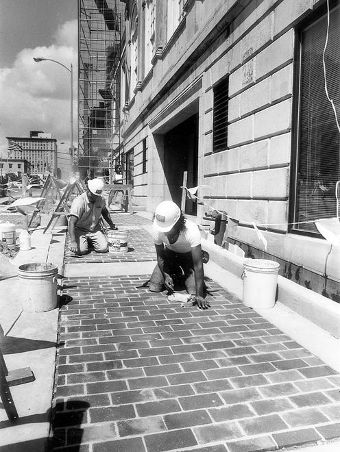 Doug Crawford, front, and Jemsey Williams working on the sidewalk of the Andrew Johnson Hotel in 1986.