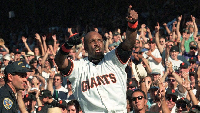 In this 1997 file photo, San Francisco Giants outfielder Barry Bonds celebrates on top of the Giants dugout after they beat the San Diego Padres to win the National League West title.