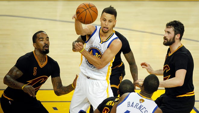 Golden State Warriors guard Stephen Curry (30) passes the ball against the defense of Cleveland Cavaliers guard J.R. Smith (5) and forward Kevin Love (0) in the first half of Game 7.