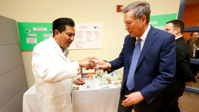 Kasich has hand sanitizer applied by Microcide Inc. President John Lopes while touring the Macomb-Oakland University Incubator at the Velocity Center on Nov. 23, 2015, in Sterling Heights, Mich.