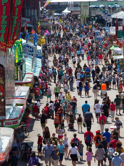 Fairgoers walk along the vendors lining the outside of the grandstand at State Fair Park.