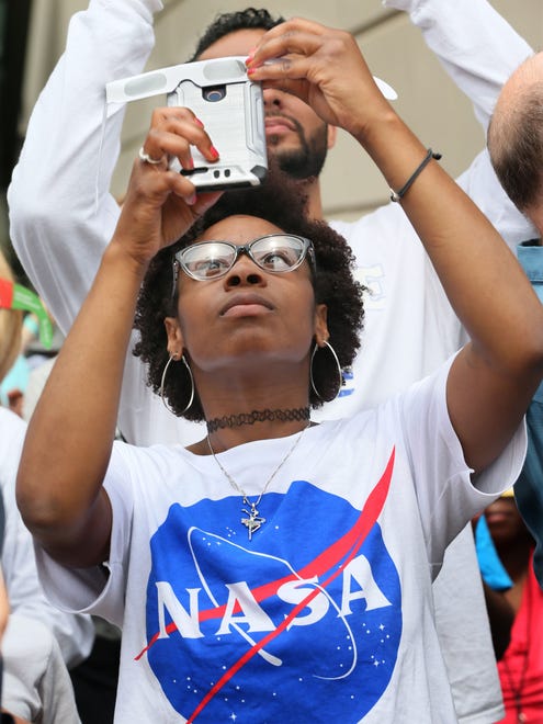 Kanisha Caldwell uses her eclipse glasses over her phone in an attempt to get a photo.