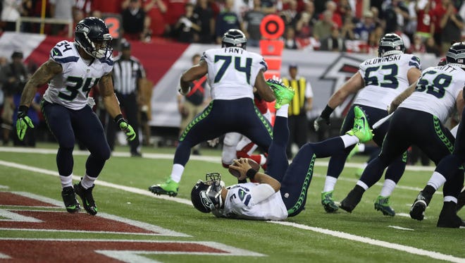 Seattle Seahawks quarterback Russell Wilson (3) is knocked into the end zone for a safety by the Atlanta Falcons during the second quarter in the NFC Divisional playoff at Georgia Dome.