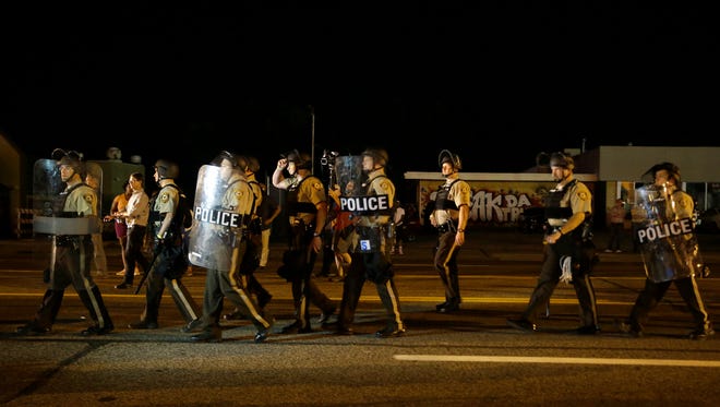 Police walk around protesters as people gather along West Florissant Street in Ferguson, Mo., on Aug. 11, 2015.