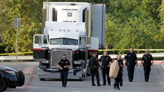 San Antonio police officers investigate the scene where multiple people were found dead in a tractor-trailer loaded with at least 30 others outside a Walmart store in stifling summer heat in what police are calling a horrific human trafficking case, July 23, 2017, in San Antonio.