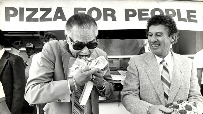 In 1985, Detroit Mayor Coleman Young eats a slice of pizza at a fundraiser for the hungry in Detroit. It was sponsored by Little Caesars Pizza, owned by Mike Ilitch..