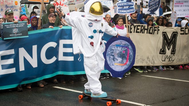 A young man dressed as an astronaut rides an electric skateboard at the head of the March for Science in Washington.