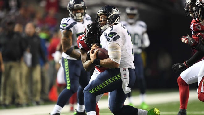 Seattle Seahawks quarterback Russell Wilson (3) is hit by Atlanta Falcons cornerback Brian Poole (34) during the fourth quarter in the NFC Divisional playoff at Georgia Dome.