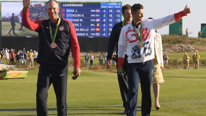 Matt Kuchar of the United States, left, walks with his bronze medal ahead of Justin Rose of Great Britain who won gold at the medal ceremony for men's individual golf at Olympic Golf Course during the Rio 2016 Summer Olympic Games.