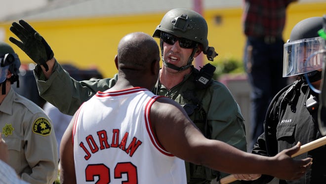 A police officer talks with a man during a protest in El Cajon, Calif.
