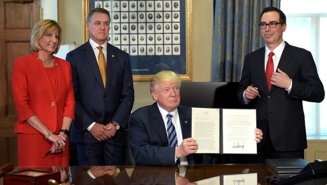 President Trump shows a memorandum he signed on Orderly Liquidation Authority at the Treasury Department on Friday, April 21, 2017. From left are Rep. Claudia Tenney, Sen. David Perdue, and Treasury Secretary Steven Mnuchin.