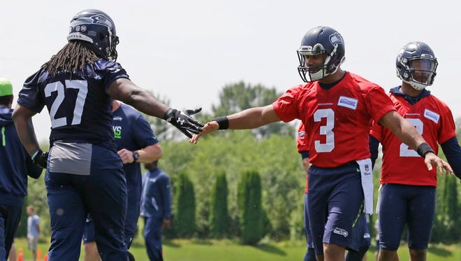 Seattle Seahawks quarterback Russell Wilson greets running back Eddie Lacy during practice in Renton, Wash.