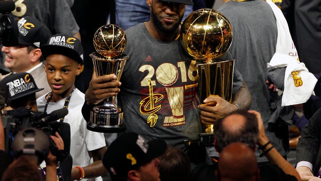 LeBron James (23) celebrates with the Larry O'Brien championship and Bill Russell MVP trophies.