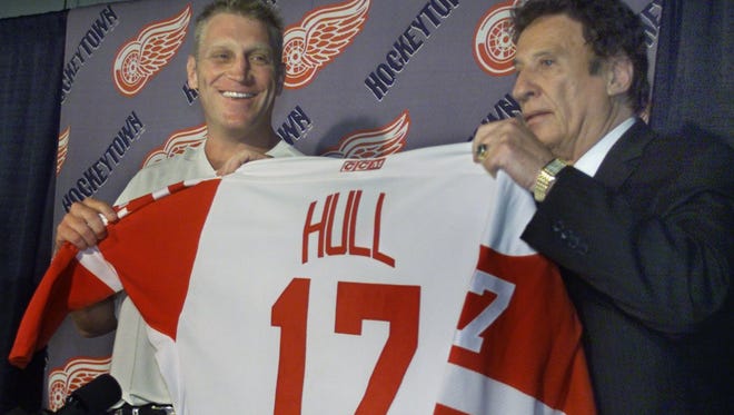 Newest Detroit Red Wing BRETT HULL is handed his new jersey by Wings' owner MIKE ILITCH during the formal press conference when he was introduced in 2001.