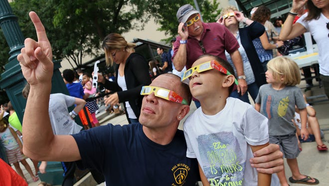 Jason Strez (left) and his son Emmanuel Strez, 6, of Milwaukee watch the eclipse through viewing glasses.