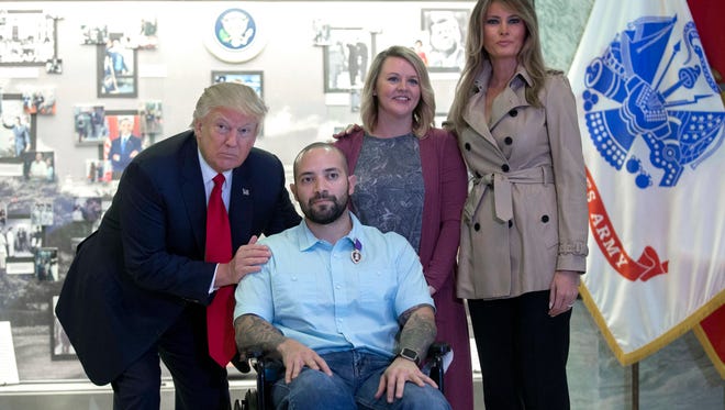 President Trump and first lady Melania Trump talks with Sergeant First Class Alvaro Barrientos and his wife Tammy after awarding the Purple Heart to him during a visit to Walter Reed National Military Medical Center in Bethesda, Maryland Saturday.