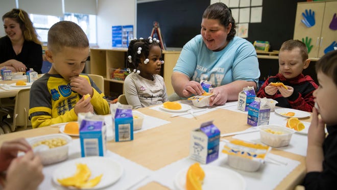 Teacher Patty Cronin helps three-year-old Makayla Grant open her package of cereal during preschool in Philadelphia, Friday, Jan. 6, 2017. Thousands of Philadelphia toddlers are starting 2017 in a city pre-kindergarten program, launched this week alongside a new sugary beverage tax created to fund it.