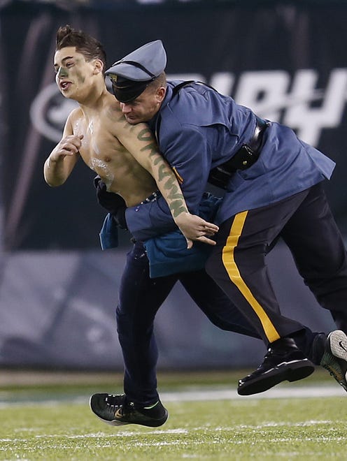 A New York Jets fan is tackled by N.J. State Police officer Brian McEnerney after running onto the field as the Jets played the Indianapolis Colts during the 2nd half at MetLife Stadium in East Rutherford, N.J.