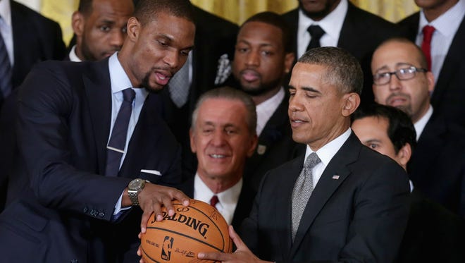 Chris Bosh presents President Barack Obama with a signed basketball during an event at the White House to celebrate the Miami Heat's second consecutive NBA title.