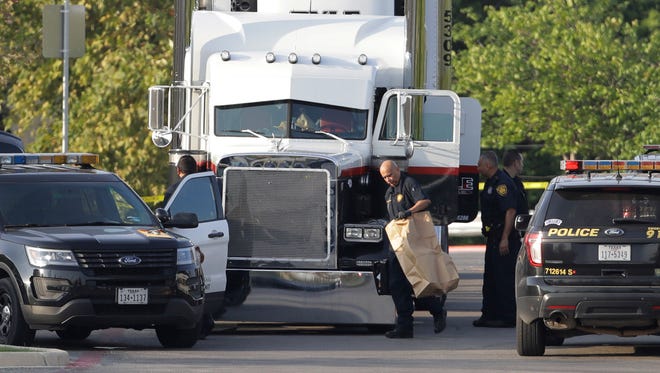 San Antonio police officers investigate the scene where multiple people were found dead in a tractor-trailer loaded with at least 30 others outside a Walmart store in stifling summer heat in what police are calling a horrific human trafficking case on July 23, 2017, in San Antonio.