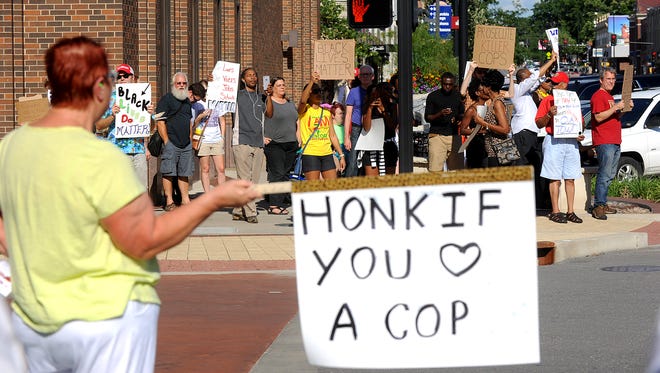 Beverley Fries of Columbia, Mo., holds a sign in support of police officers across the street from a Black Lives Matter protest, on Aug. 12, 2015.