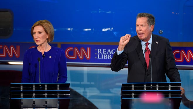 Carly Fiorina looks on as Kasich speaks during the CNN Republican presidential debate at the Ronald Reagan library on Sept. 16, 2015, in Simi Valley, Calif.