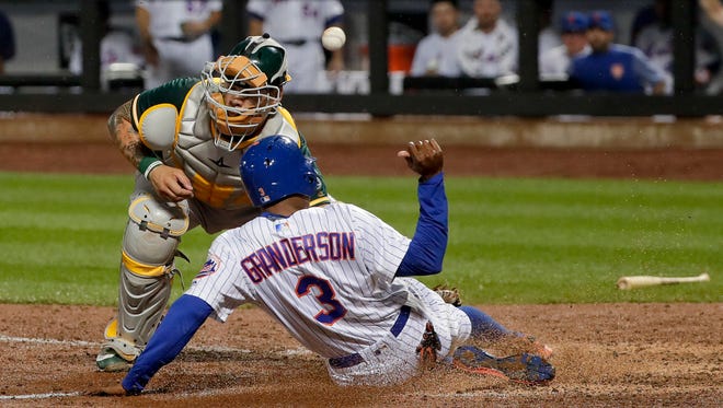 New York Mets' Curtis Granderson (3) slides safely into home plate as the ball skips away from Oakland Athletics catcher Bruce Maxwell during the sixth inning of a baseball game, Saturday, July 22, 2017, in New York. Grandson scored on a double by Michael Conforto.