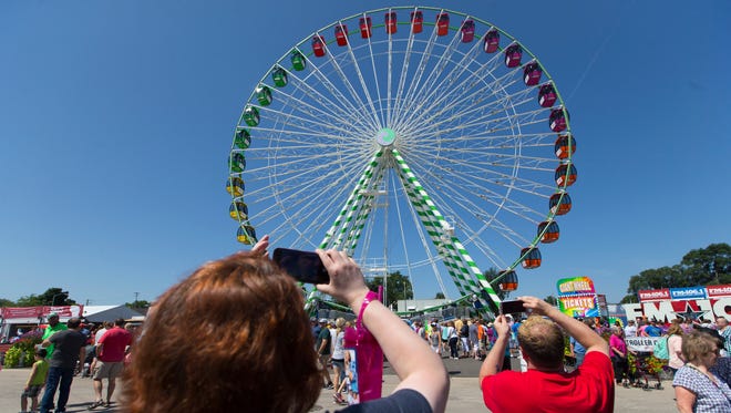 Fairgoers photograph a Ferris wheel at State Fair Park in West Allis. Before this year, the site of the Ferris wheel was the west market, which was razed by the park because the space was underutilized.