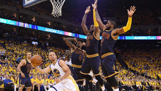 Golden State Warriors guard Stephen Curry (30) passes the ball against Cleveland Cavaliers forward LeBron James (23) and guard Kyrie Irving (2) during the third quarter in Game 2.