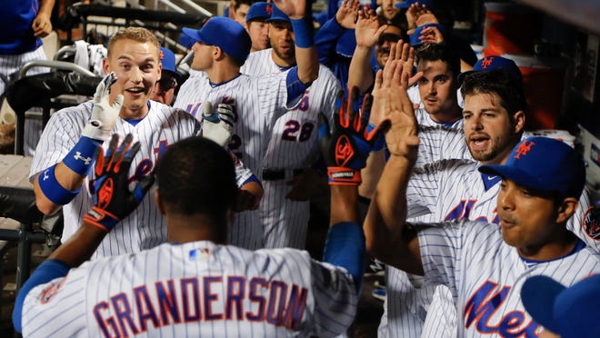 Mets' Curtis Granderson (3) is greeted by teammates in the dugout after hitting solo home run against the Minnesota Twins during the eleventh inning. He won the game with a homer in the 12th.