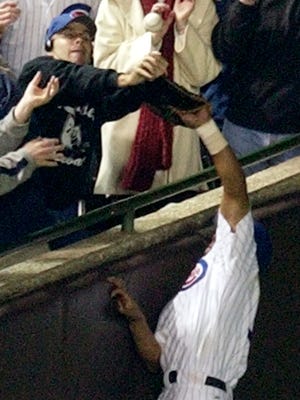 Chicago Cubs' Moises Alou tries to catch a foul ball as Steve Bartman reach as well during the 2003 National League Championship Series.