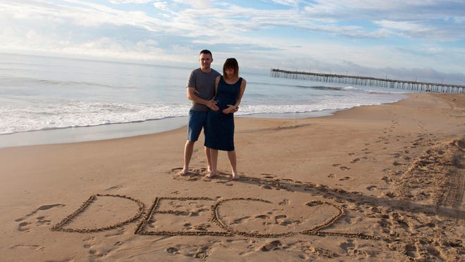 Ashley May and her husband, Curtis, announced their due date with this photo taken at Virginia Beach.