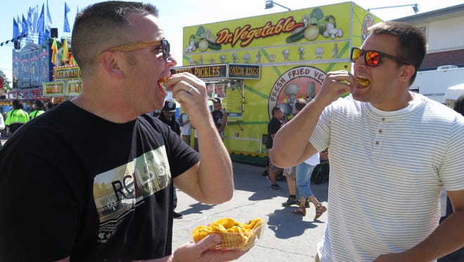 Steve Janetski (left) and Jordan Mikkelsen taste cricket nachos from All Things Jerky at the Wisconsin State Fair.