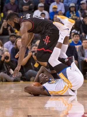 Houston Rockets guard James Harden (13, top) and Golden State Warriors forward Draymond Green (23, bottom) tangle after a jump ball call in a recent game.