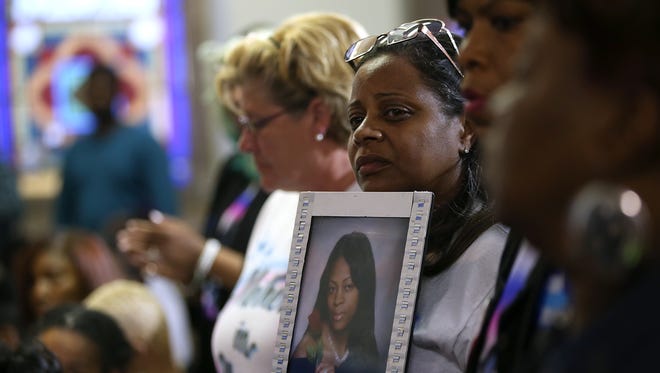 A woman holds a photo of a victim of gun violence as Democratic presidential candidate Hillary Clinton speaks during a panel discussion on gun violence.