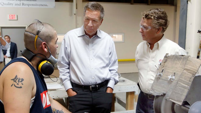 Kasich talks with Harley Staples, left, during a visit at RP Abrasives on July 13, 2015, in Rochester, N.H.