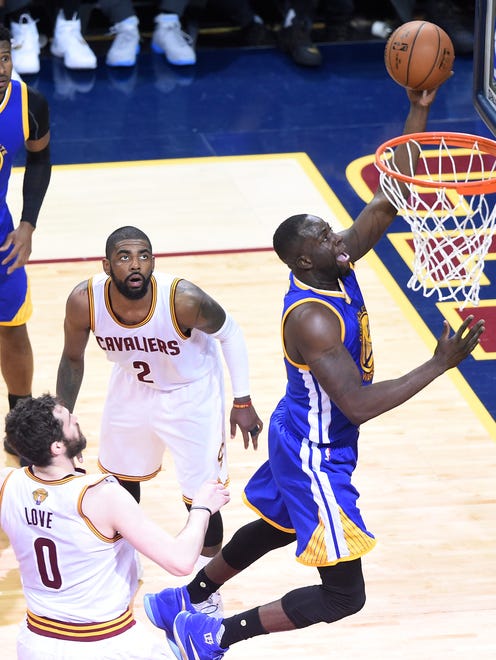 Golden State Warriors forward Draymond Green (23) shoots the ball in front of Cleveland Cavaliers forward Kevin Love (0) and guard Kyrie Irving (2) during the second quarter in Game 6 of the NBA Finals at Quicken Loans Arena.