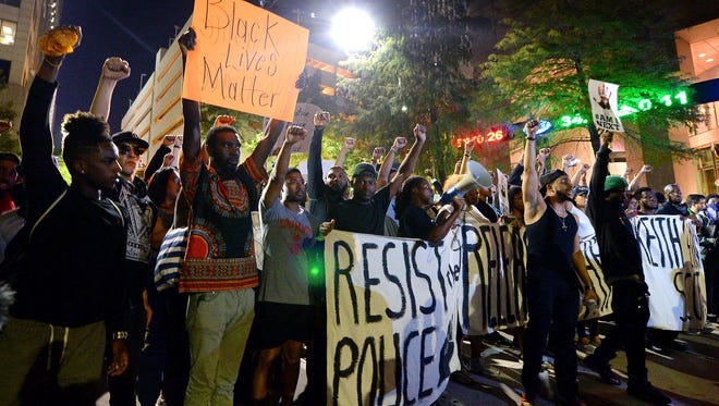 Protesters stand in unity in Charlotte on Friday as they prepare to march throughout the city to protest Tuesday's fatal police shooting of Keith Lamont Scott.